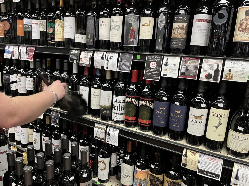 Rep dusting wine bottles on shelf